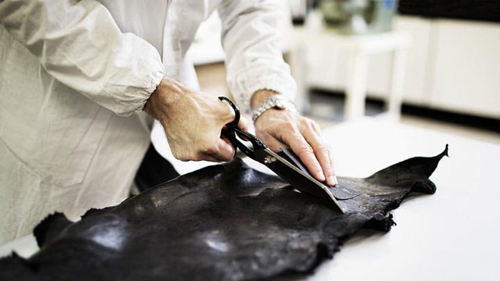 Woman cutting a piece of raw material on table