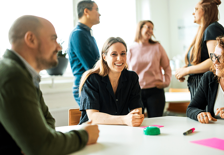 Smiling female by the table with people around her
