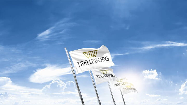 Trelleborgs flaggor vajar mot en blå himmel och representerar företagets huvudkontor